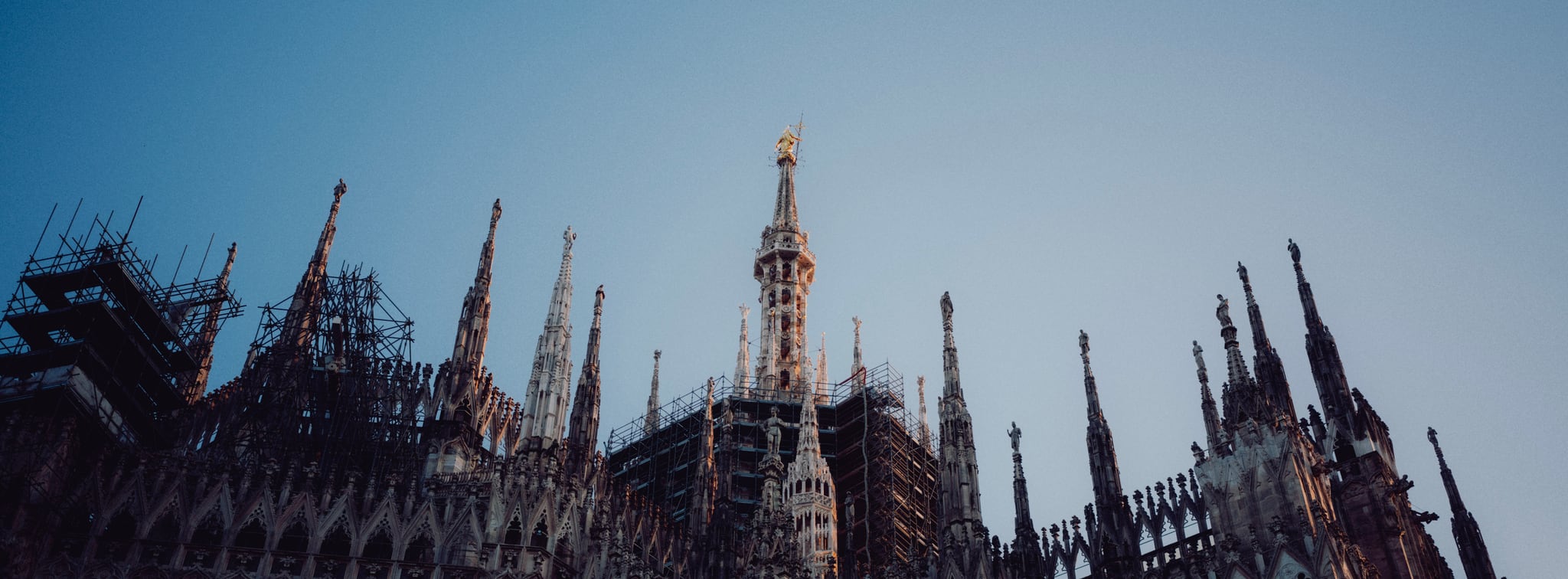 Ornate Gothic spires and rooftop details rise against a pale blue sky.