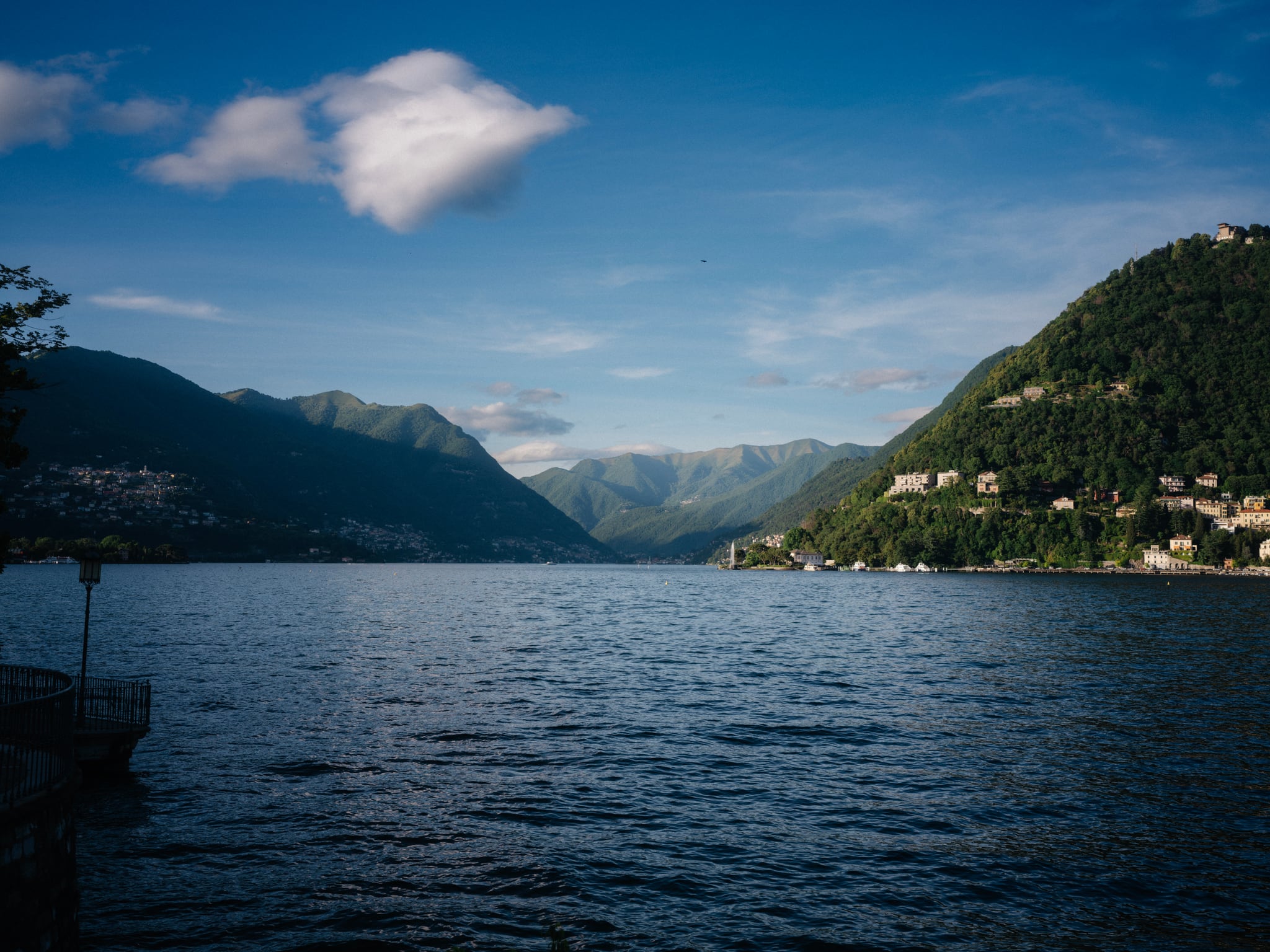 A broad lake lies between wooded mountains, with scattered buildings along the shore.