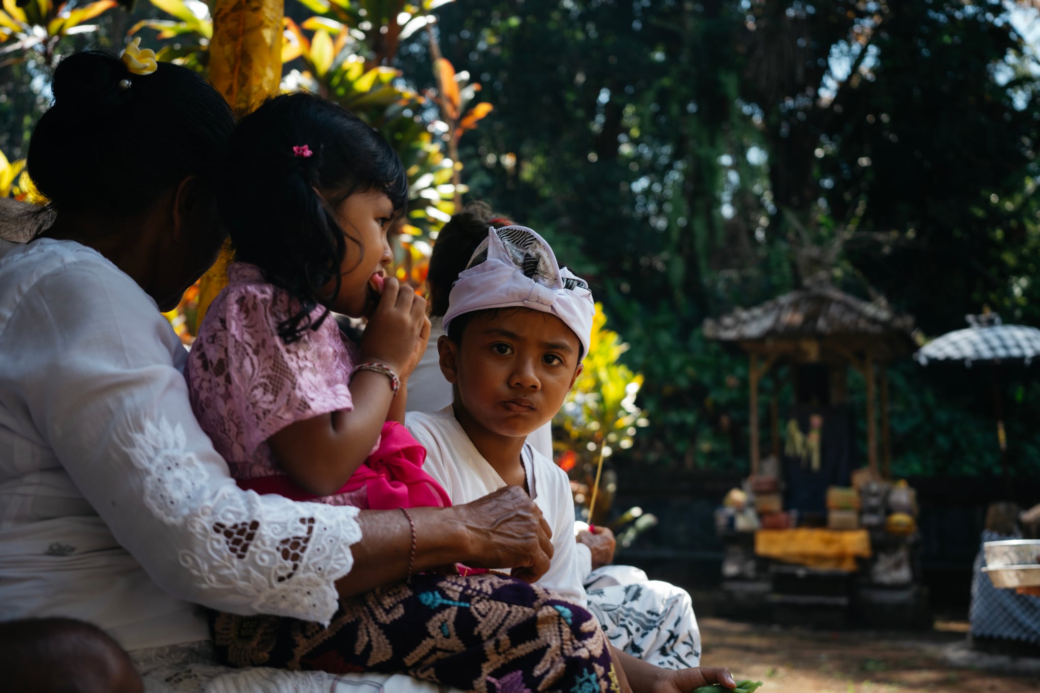 People sit close together beside bright flowers and garden plants in Bali.