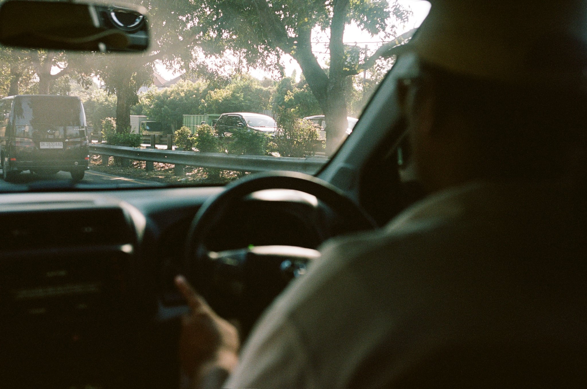 Sunlight falls across a driver and steering wheel inside a vehicle.